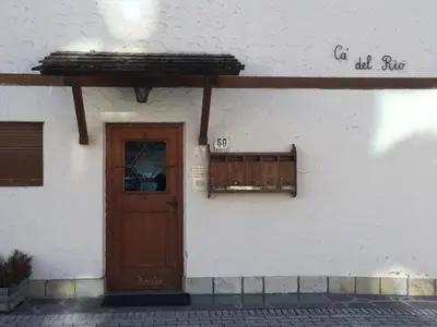 a white building with a wooden door and a window at Casa Pecol in Cortina dʼAmpezzo
