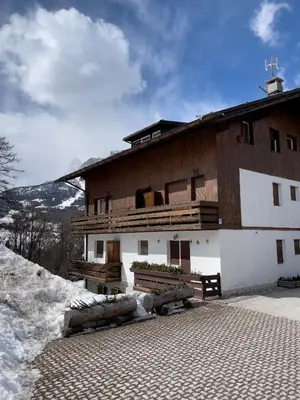 a large wooden building with snow in front of it at Casa Pecol in Cortina dʼAmpezzo