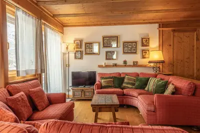 a living room with a red couch and a tv at Casa Pecol in Cortina dʼAmpezzo