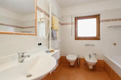 a bathroom with a tub and a toilet and a sink at Garnì Sirio in Colfosco