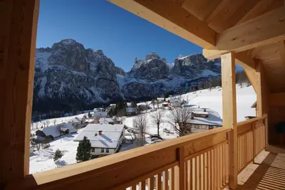 a view from a log cabin balcony with snow covered mountains at Garnì Sirio in Colfosco