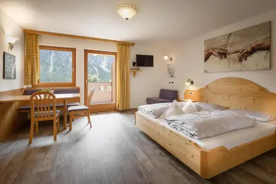 a bedroom with a wooden bed and a desk at Garnì Sirio in Colfosco