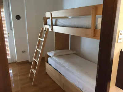 two bunk beds in a room with a ladder at Spazioso e accogliente nel centro di Merano in Merano