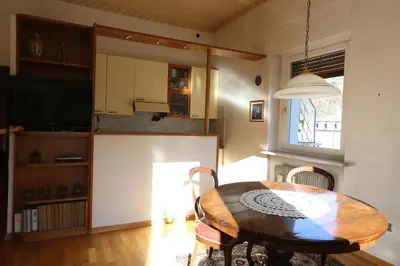 a living room with a table and a kitchen at Spazioso e accogliente nel centro di Merano in Merano