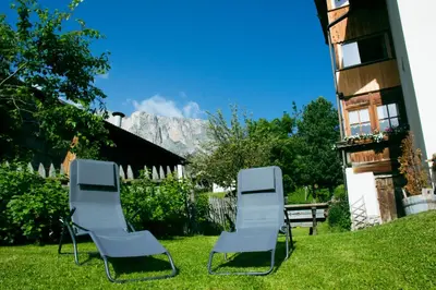 two chairs and a bench in a yard with a mountain at Appartamenti Sotgherdena in Badia