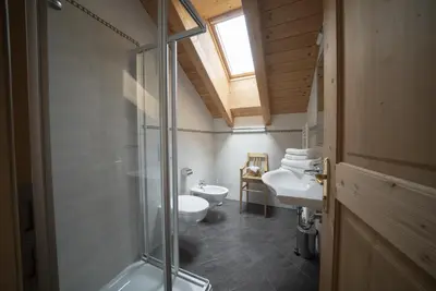 a bathroom with two toilets and a sink and a shower at Appartamenti Sotgherdena in Badia