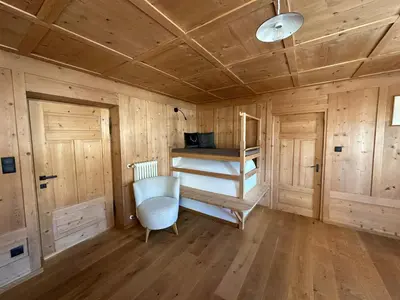 a room with a bunk bed and a chair in it at Appartamenti Sotgherdena in Badia