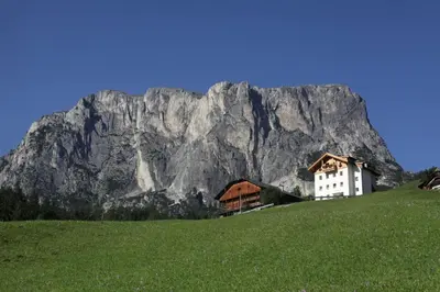 a house on a hill with a mountain in the background at Appartamenti Sotgherdena in Badia