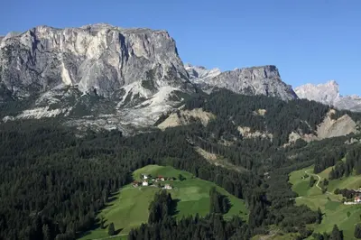 a mountain range with a green field and trees at Appartamenti Sotgherdena in Badia