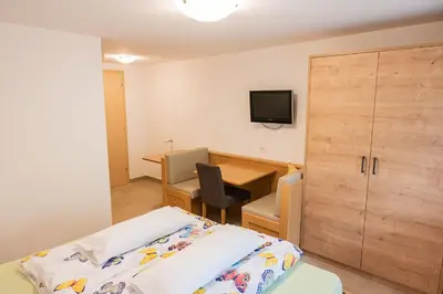 a bedroom with a bed and a desk and a tv at Garni Birkenau in San Martino