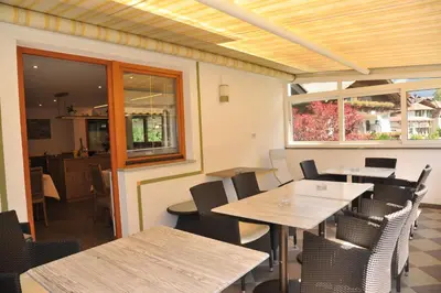 a restaurant with wooden tables and chairs and windows at Garni Birkenau in San Martino