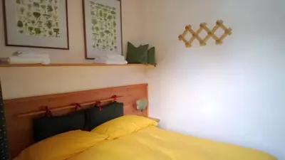 a bedroom with a bed with a yellow pillow at Freetime PinkAlps in Arabba