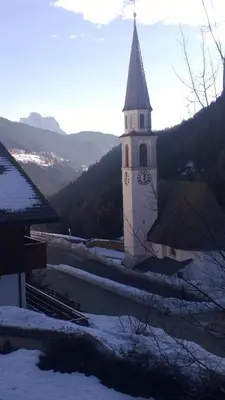 a church with a clock tower in the snow at Freetime PinkAlps in Arabba