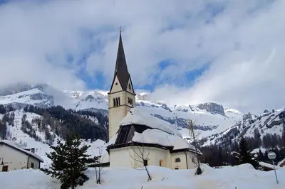 a church in the snow with mountains in the background at Freetime PinkAlps in Arabba