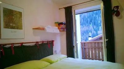 a bedroom with a bed and a large window at Freetime PinkAlps in Arabba