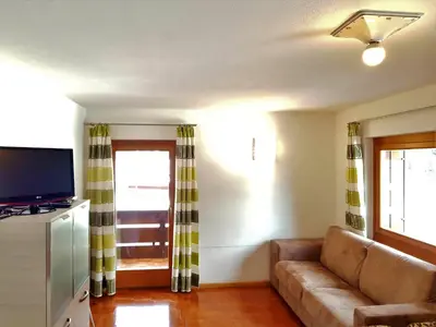 a living room with a couch and a television at Residence La Zondra in Pozza di Fassa