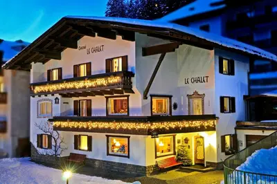 a building covered in christmas lights in the snow at Garni Le Chalet in Santa Cristina in Val Gardena