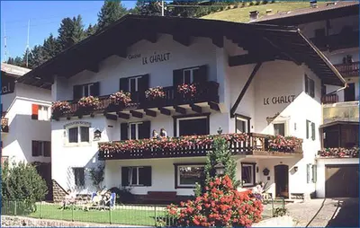 a large white building with flowers on the balcony at Garni Le Chalet in Santa Cristina in Val Gardena