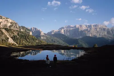 two people standing in front of a lake in the mountains at Garni Le Chalet in Santa Cristina in Val Gardena