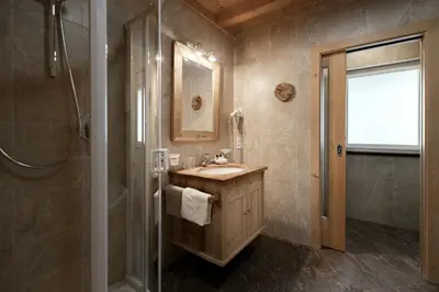 a bedroom with a bed and a wooden nightstand with a lamp at Apartments Isgla in Selva di Val Gardena