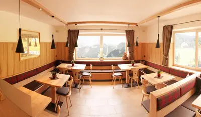 a restaurant with wooden tables and chairs and a window at Garni Martlhof in Selva di Val Gardena