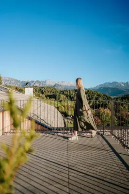 a woman walking on a bridge with the mountains in the background at Hotel am Hang in Soprabolzano