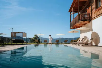 a woman is standing next to a swimming pool at Hotel am Hang in Soprabolzano