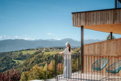 a woman standing on the balcony of a house at Hotel am Hang in Soprabolzano