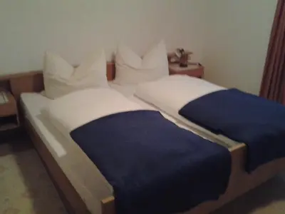 a bed with a blue and white blanket and pillows at Schartnerhof in Collalbo