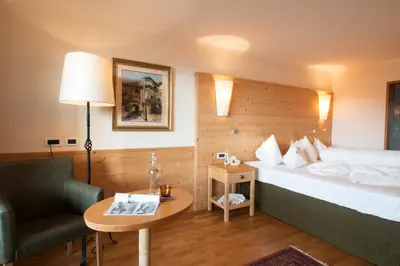a hotel room with a bed and a chair and a table at Schwarzer Adler in Siusi