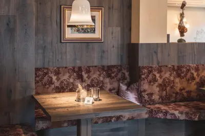 a wooden table in a restaurant with a lamp at Schwarzer Adler in Siusi