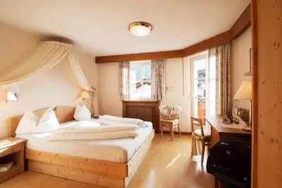 a bedroom with a bed and a desk and a table at Schwarzer Adler in Siusi