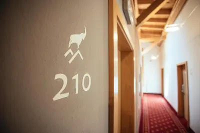 a sign on the wall of a hallway with a deer on it at Hotel Wildschütz in San Leonardo in Passiria