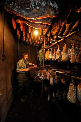 a man standing in a room with a bunch of meat at Hotel Wildschütz in San Leonardo in Passiria