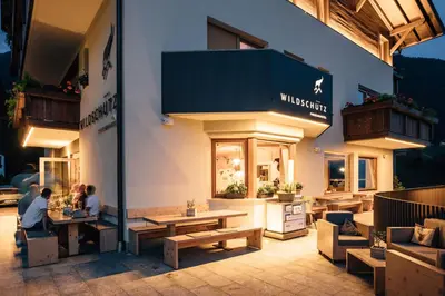 two people sitting at tables outside of a store at Hotel Wildschütz in San Leonardo in Passiria