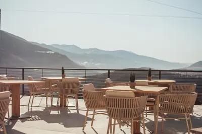 a row of tables and chairs on a balcony with mountains at Hotel Schönblick in Rodengo