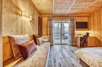 a bedroom with wooden walls and a bed and a tv at Hotel Pustertalerhof in Chienes