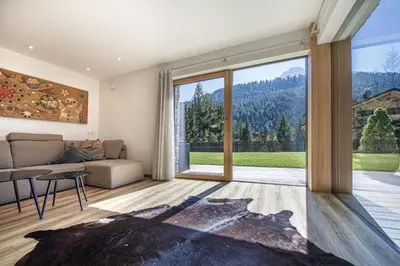 a living room with a couch and a large window at Apartment Villa Valeria in Selva di Val Gardena