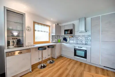 a kitchen with white cabinets and stainless steel appliances at Apartment Villa Valeria in Selva di Val Gardena