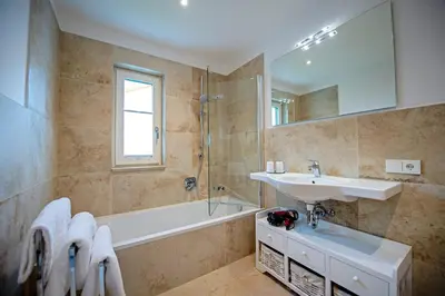 a bathroom with a sink and a mirror and a tub at Apartment Villa Valeria in Selva di Val Gardena