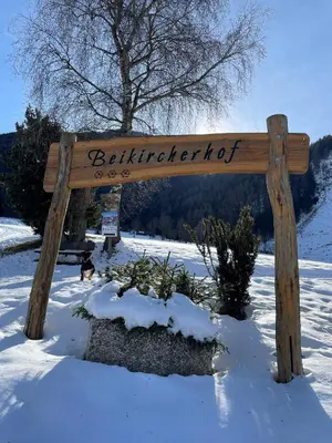 a wooden sign with the name of a beehiveintendent in the snow at Beikircherhof in San Lorenzo di Sebato
