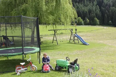 a little boy sitting on a toy tractor next to a playground at Beikircherhof in San Lorenzo di Sebato