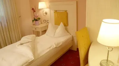 a small room with two beds and a lamp at Hotel Stella Montis in Campitello di Fassa