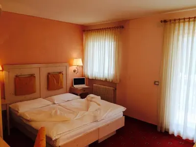 a bedroom with a bed and a desk with a computer at Hotel Stella Montis in Campitello di Fassa