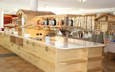 a large wooden bar in a restaurant with a counter at Hotel Stella Montis in Campitello di Fassa
