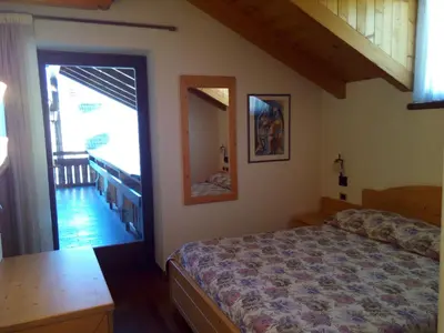 a bedroom with a blue bed and a door at B&B Casa Bazzanella in Cavalese