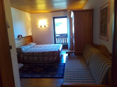 a bedroom with a bed and a window and a door at B&B Casa Bazzanella in Cavalese