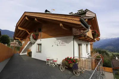 a building with a balcony with a table and chairs at Villa Prafiorì in Cavalese