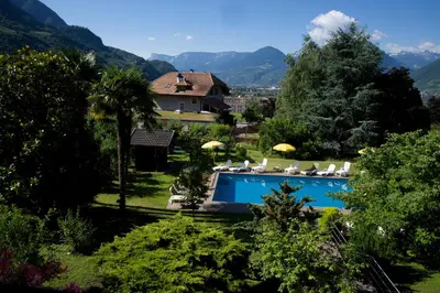 a swimming pool in a yard with a house at Hotel Tannerhof in Merano