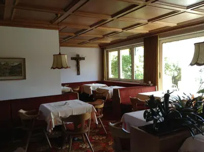 a dining room with tables and a cross on the wall at Hotel Tannerhof in Merano